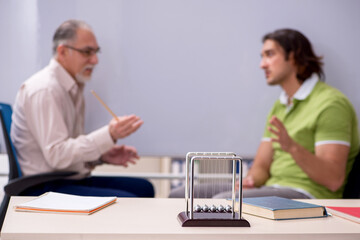 Old professor physicist and young student in the classroom