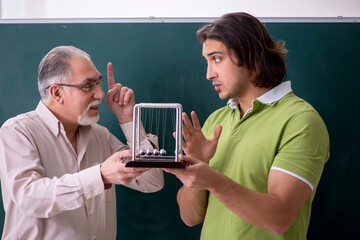 Old professor physicist and young student in the classroom