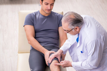 Obraz premium Young male patient visiting old doctor traumatologist
