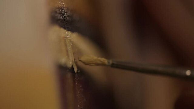 The artist paints with a brush on canvas in room light. Close-up of a brush.