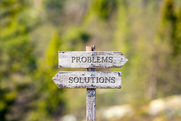 problems solutions text carved on wooden signpost outdoors in nature. Green soft forest bokeh in the background.