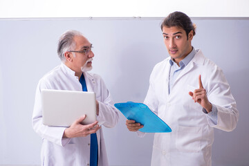 Experienced doctor teaching young male assistant using computer