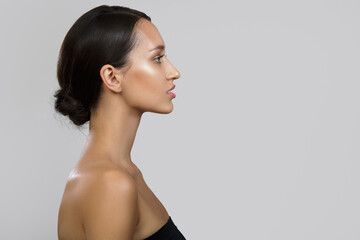 Young brunette woman portrait. Bare shoulders. Side view