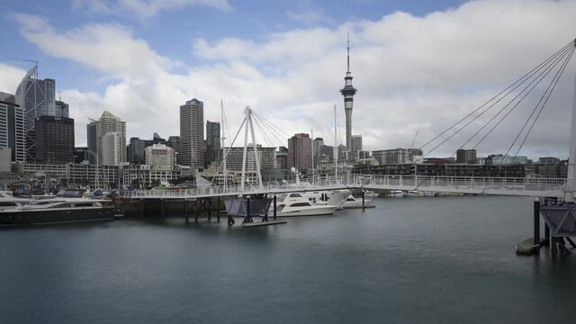 A panning time-lapse of the Wynyard Crossing double bascule pedestrian/cycling bridge at the Viaduct Harbour with the downtown Auckland City skyline behind. Auckland, New Zealand.