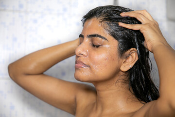 Fototapeta premium Indian Mexican Lady Bathing hair wash her hairs massaging hair and body with hands visible soap lather water dripping from her nude body posing with smiling face posing her long black hairs in corona
