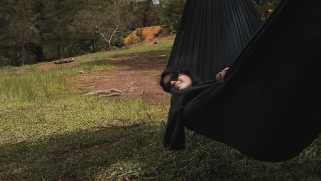 Young woman rests on an amaca while camping on the mountain inside a forest