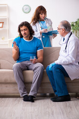 Fototapeta premium Two doctors visiting sick young man at home