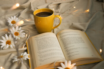 Naklejka na ściany i meble cup with black coffee, yellow open book, daisies and warm lights
