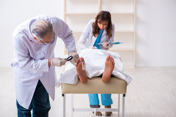 Police coroner examining dead body corpse in morgue
