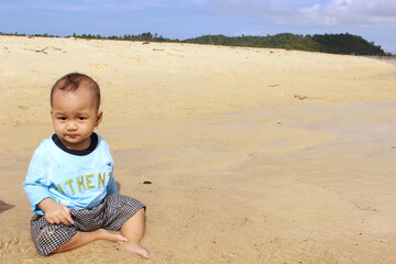 A beautiful cute little girl taste the sea water and make an expression on the beach