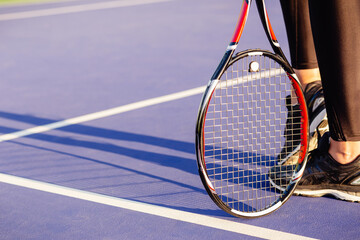 Legs of female tennis player racket.