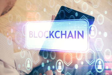 Double exposure of man's hands holding and using a phone and crypto currency blockchain theme...