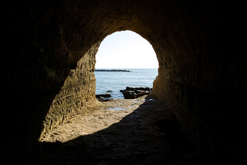 Sunshine into the rock cave in the cliff on anzio beach, Rome in Italy
