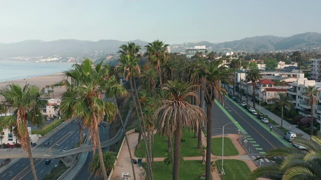 Drone is fling along the Santa Monica green park and Pacific Highway with scenic landscape on a background. COVID-19 outbreak lockdown, quarantine of the health disease. 4K aerial beach and mountains
