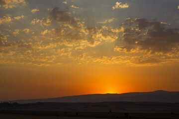 Sunset cloudy sky with the orange sun