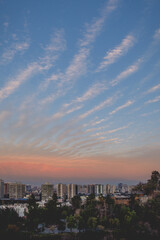 Fototapeta premium Beautiful pattern of clouds and sunset sky over Santiago downtown and Los Andes mountains with golden sunlight, Santiago de Chile