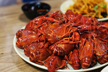 close up many steamed spicy Red Swamp Crayfish in plate on table. blur background. popular food in China