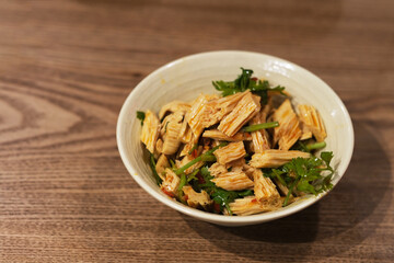 close up a bowl of cold bean curd stick on table. A kind of spicy cold dish in China. bean curd stick mix with cilantro