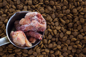 Dry,adult dog food with vitamin and uncooked chicken.Above view,background.