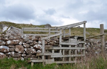 Timber stile for crossing over stone boundary wall in field on the Isle of Skye in Scotland
