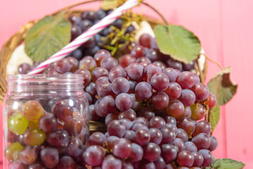 Bunches and grains of the Vitis vinifera variety on pink background