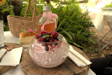 Ice and berries with cheesecake and a bottle of syrup in the background