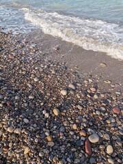 Fototapeta na wymiar Colored stones and waves of the sea