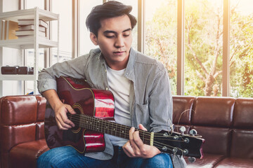 Young guitar player holding his guitar at home. Music and song concept.