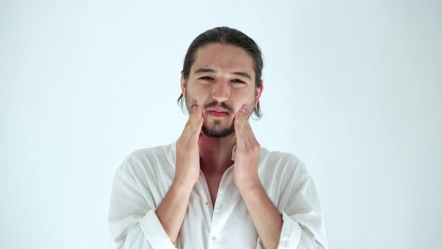 Portrait of sick young man having strong toothache, holding his cheeks with hands isolated over white background in studio. Concept of dental problems,  Tooth decay.
