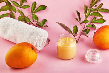Scented candle for Spa and home with a mango scent and green leaves on a pink background