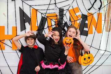 Happy Halloween by a group of children, brother and sister in carnival costume in decorated house