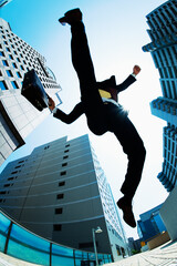 ビル街でジャンプするビジネスマン