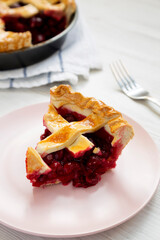 Yummy Homemade Cherry Pie on a pink plate on a white wooden table, low angle view. Close-up.