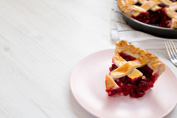 Yummy Homemade Cherry Pie on a pink plate on a white wooden background, low angle view. Space for text.