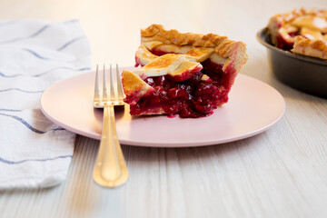 Slice of Yummy Homemade Cherry Pie on a pink plate on a white wooden background, side view. Close-up.