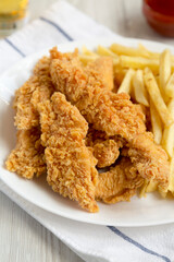 Homemade Crispy Chicken Tenders and French Fries with sauce and glass of cold beer, side view. Close-up.