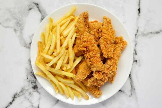 Homemade Crispy Chicken Tenders and French Fries on marble background, top view. Flat lay, overhead, from above.