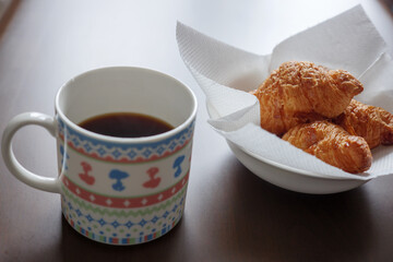 マグカップに入れたコーヒーと皿に入れたクロワッサン