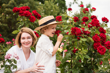 Mothers day. Young woman hugging little boy in rose garden. Beautiful and happy family. Lifestyle portrait of mom and son. Family time together