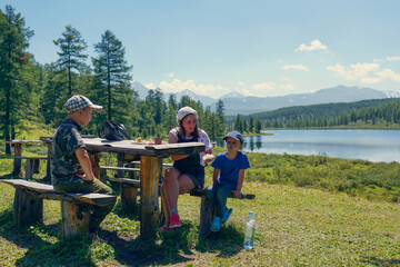 family eating on a lake shore