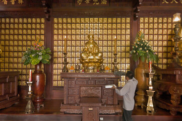 Homme époussetant un autel dans une pagode