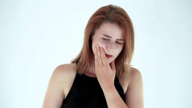 Portrait of sick young woman feeling pain, holding her cheek with hand isolated over white background in studio. Concept of dental problems,  tooth decay.