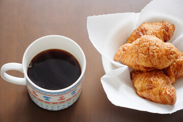 マグカップに入れたコーヒーと皿に入れたクロワッサン