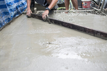 Leveling concrete with trowels, laborer spreading poured concrete