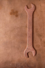 Copper wrench isolated on a copper surface. Aircraft tool. Copy space. Monochrome image. Minimalism. Vertical image.