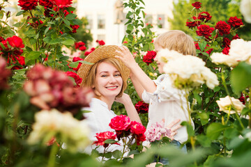 Mothers day. Young woman hugging little boy in rose garden. Beautiful and happy family. Lifestyle portrait of mom and son. Family time together