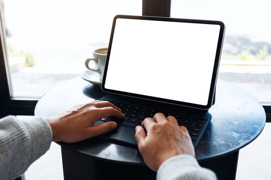 Mockup image of a woman using and typing on tablet keyboard with blank white desktop screen as a computer pc on the table