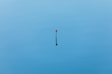 Tall fishing vivid or colorful float on the blue water surface of lake, river or pond in bright sunny day