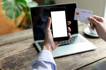 Woman hand holding credit card and using smart phone with laptop computer Online shopping concept