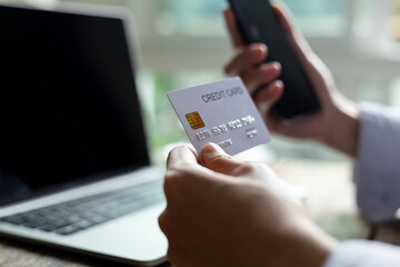 Woman hand holding credit card and using smart phone with laptop computer Online shopping concept